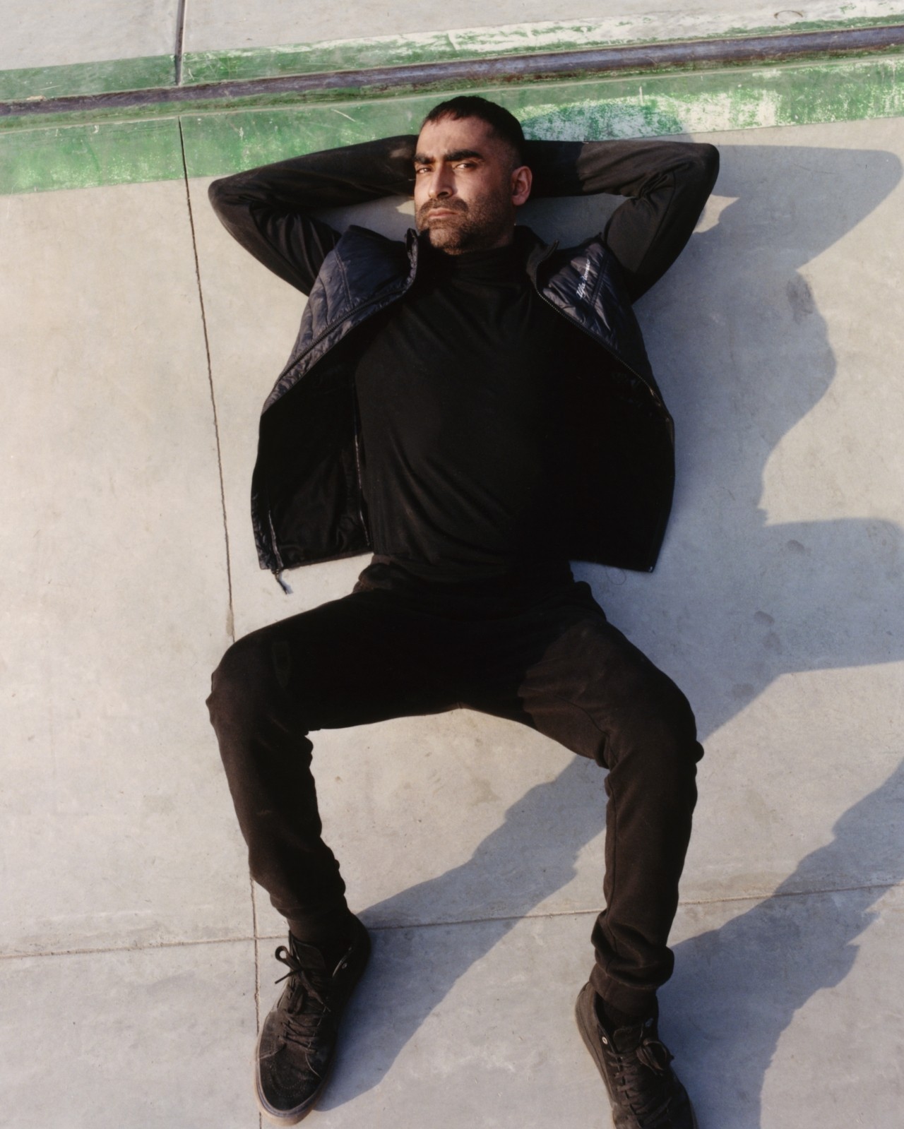 A Pakistani skater lays down in a skatepark.