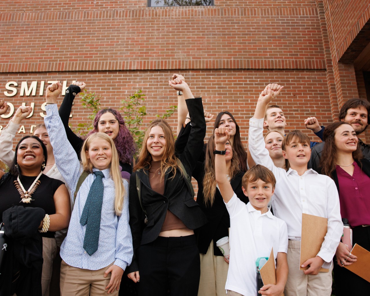 a group of kids raising fists outside a courthouse