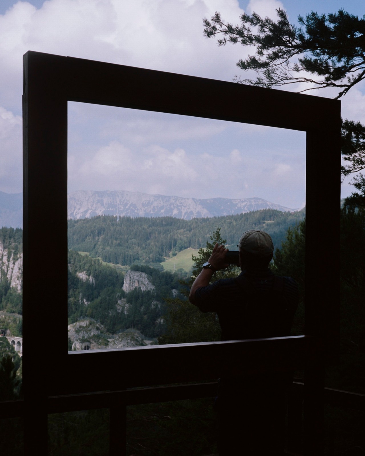 A person takes a photo of a mountain landscape.