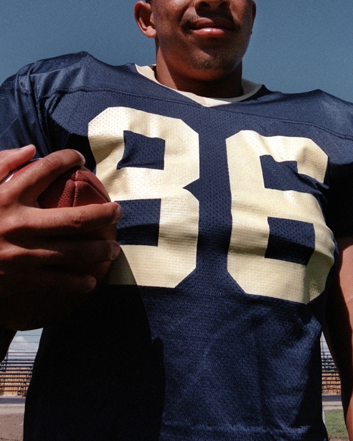 a man in a football jersey holding a football in his right hand