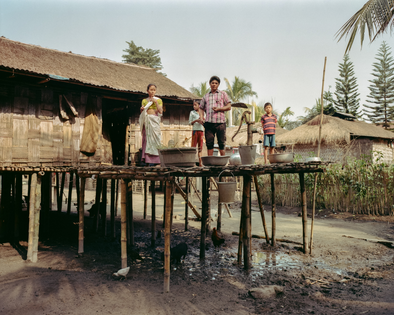 A family stands outside their house on the river.