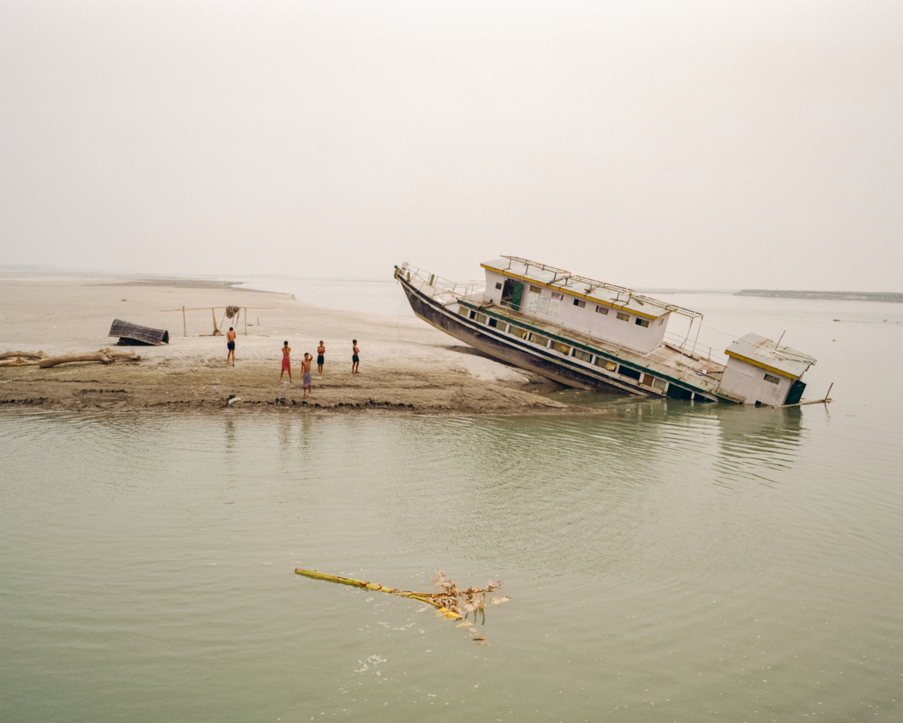 A boat is submerged partially in the water and the rest is on land.
