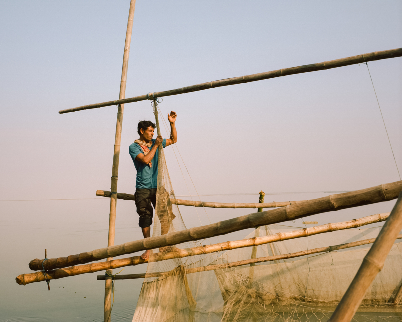 A man stands near the top of a hand made ship.