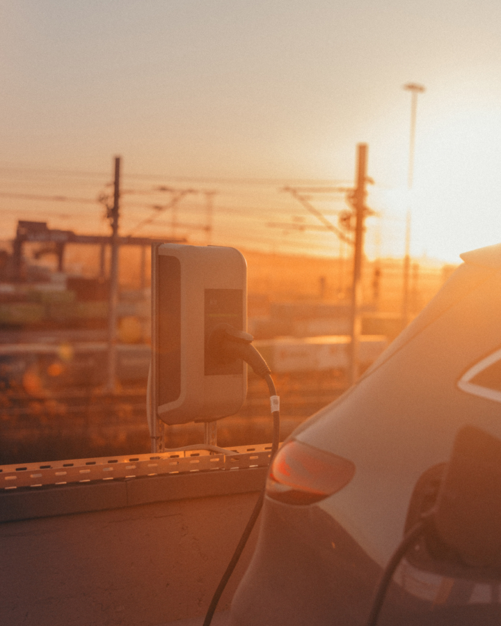 An electric vehicle is being charged as the sun sets.
