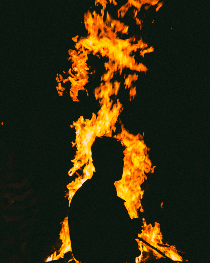 The shadow of a man stands in front of a large fire flame.