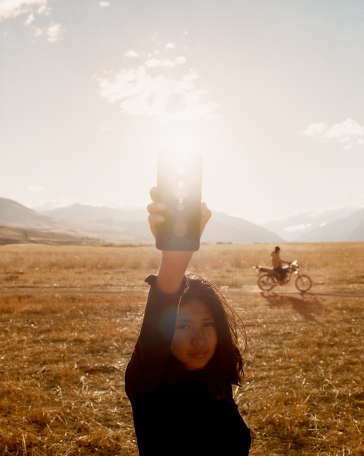 A teenager holds their phone to the light.