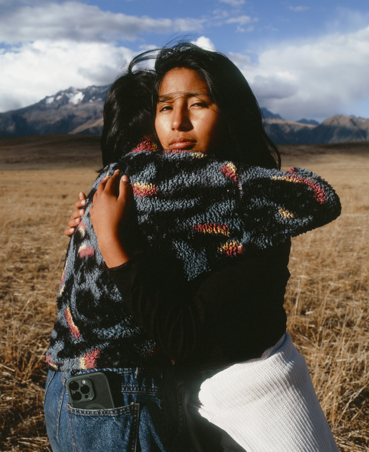 Two teenagers hug on a field.