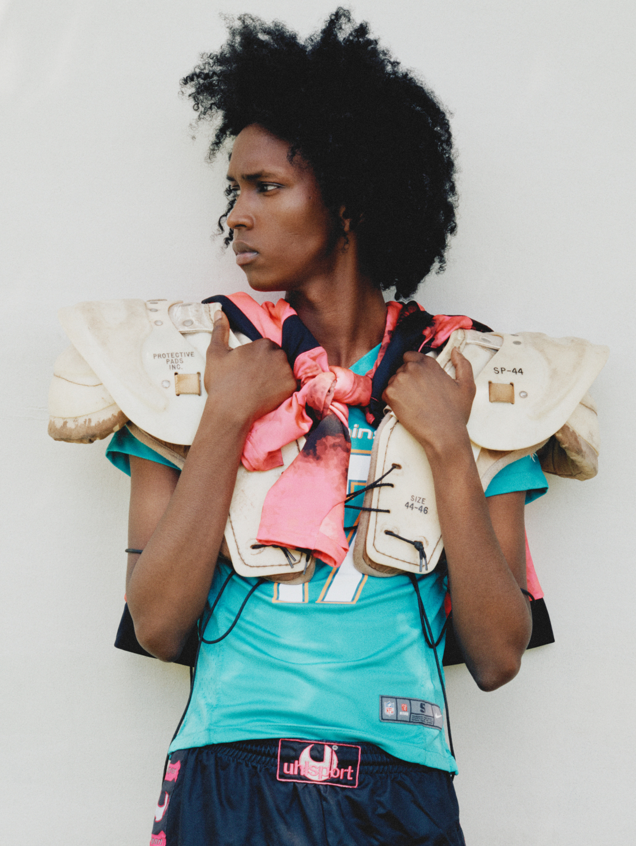 Thursday wears vintage football pads, US Salernitana 1919 jersey around neck, vintage Nike Miami Dolphins jersey, vintage Uhlsport shorts