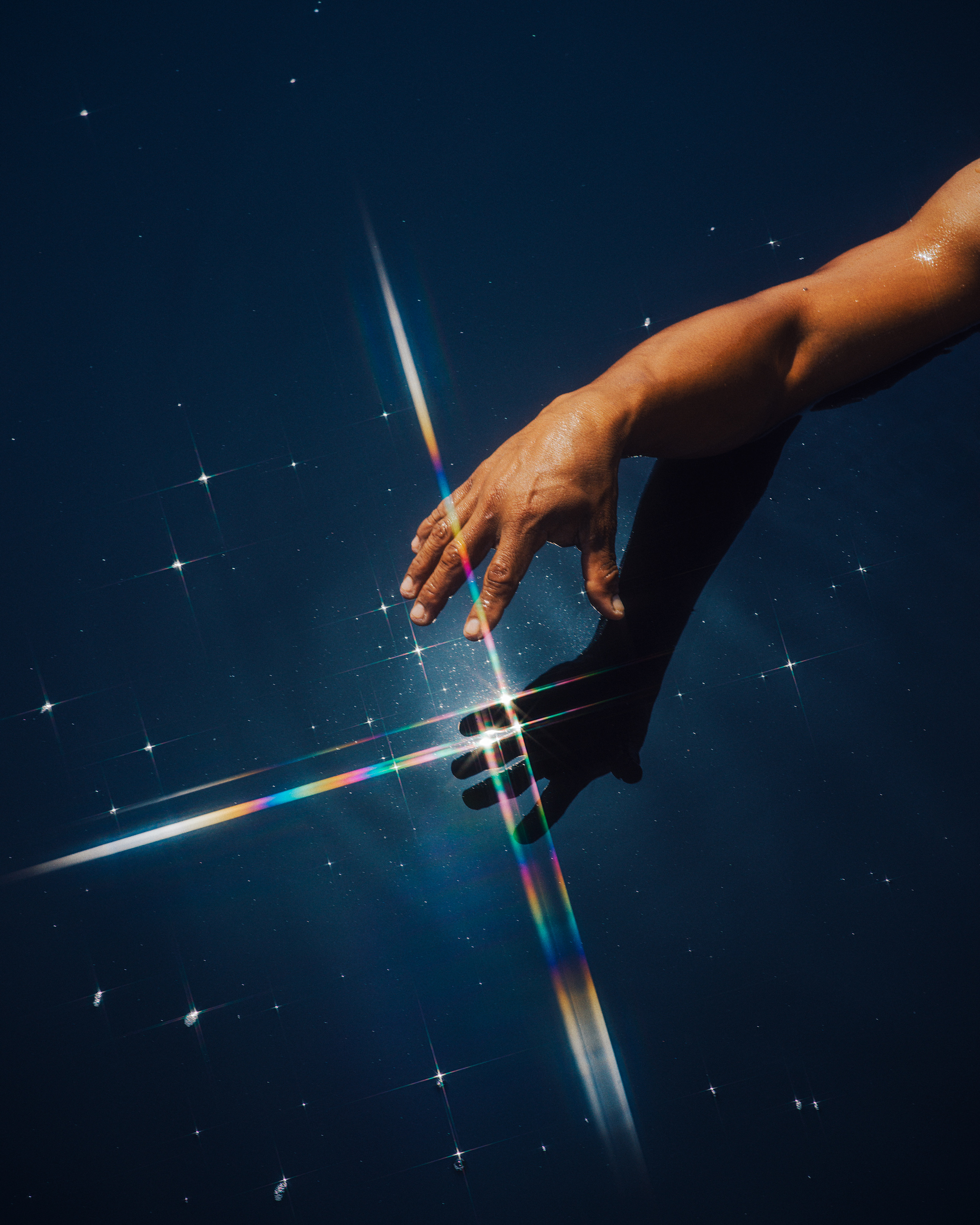 A hand reaches toward a starry blue surface.