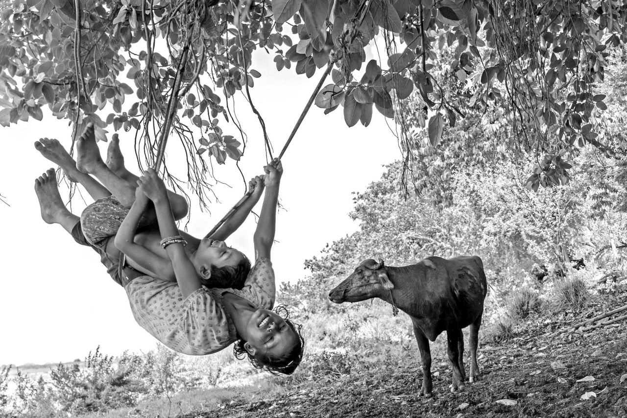 Children of the Diyara river island make their own joy, swinging on makeshift swings hung from trees.