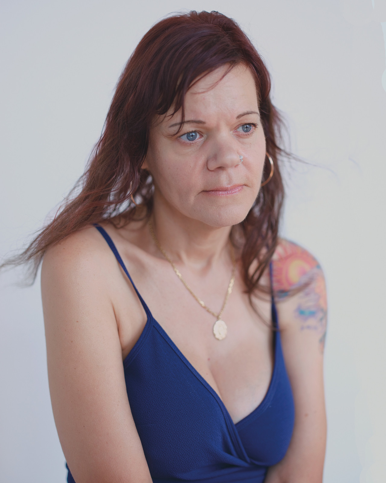 A mother wearing a blue top looks into the distance.