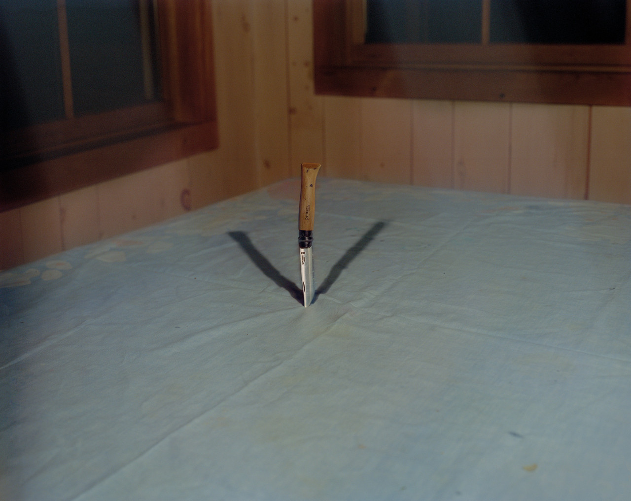 A knife sticks out of the surface of a blue mattress.