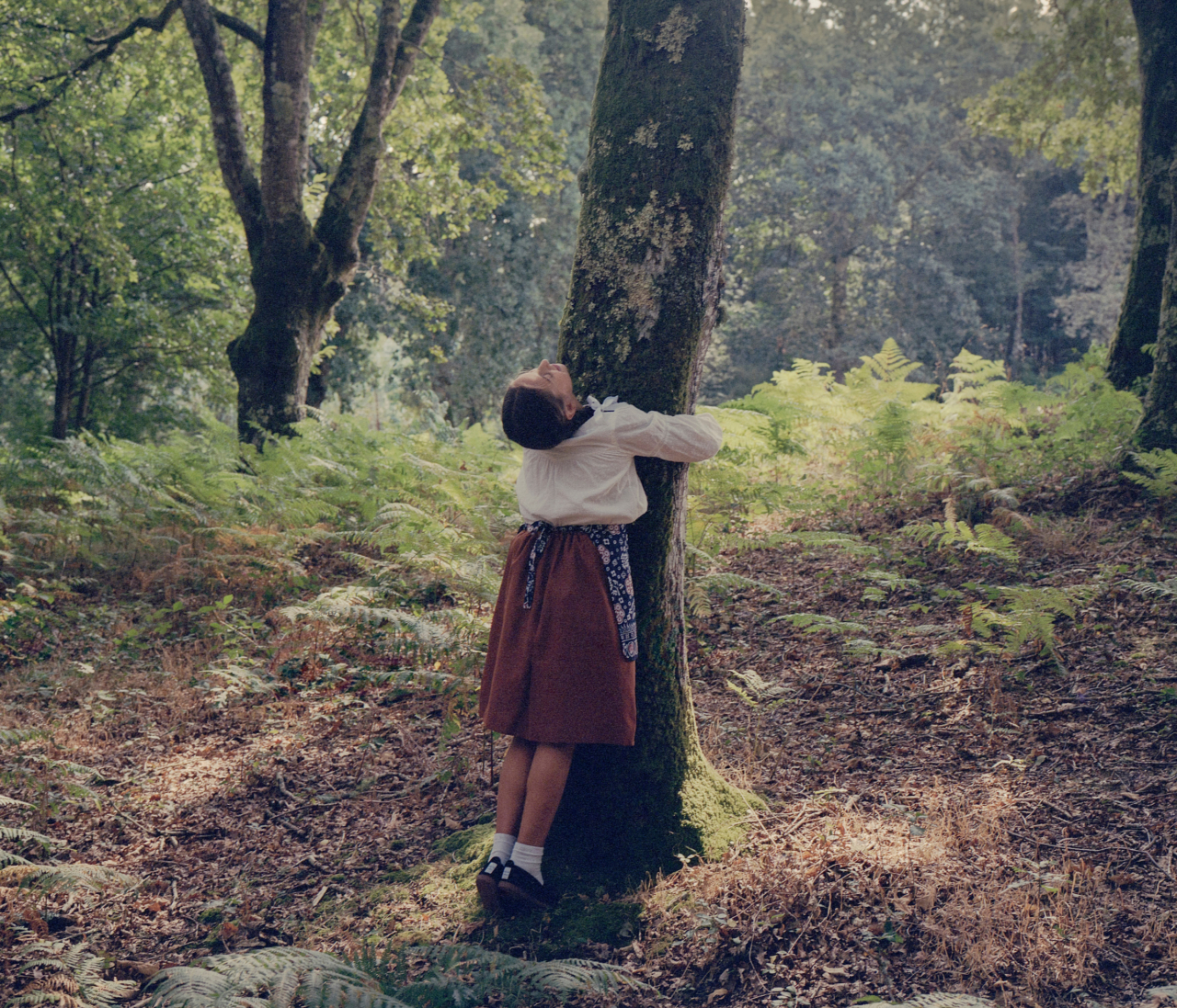 Sabela, a young Galician girl, plays in the forests of Palas de Rey, hugging a tree.
