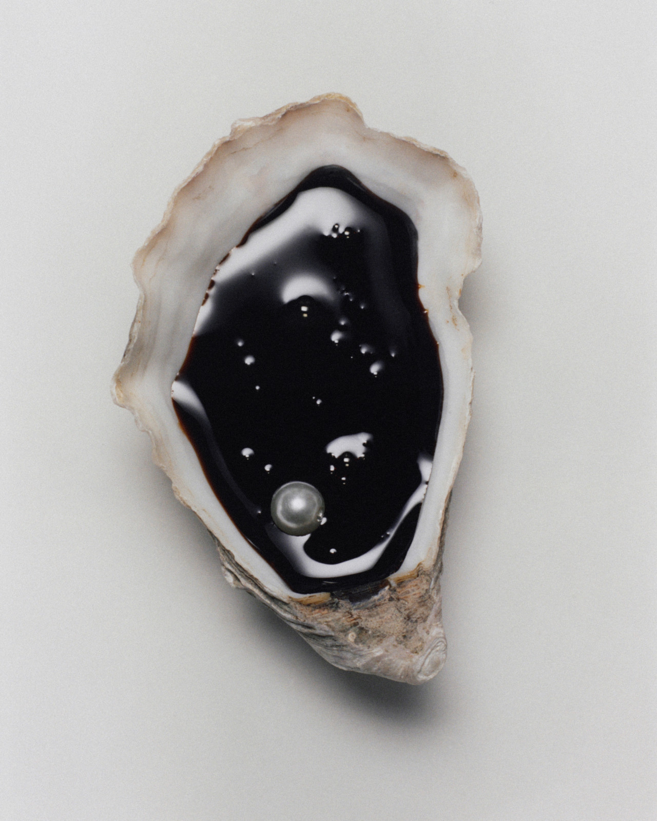 An open seashell filled with black oil.