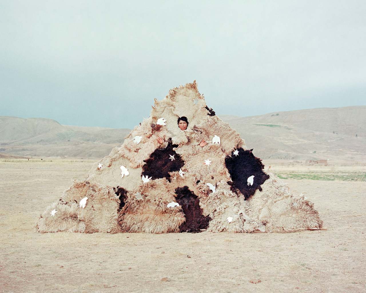 A female farmer covered in sheepskins.