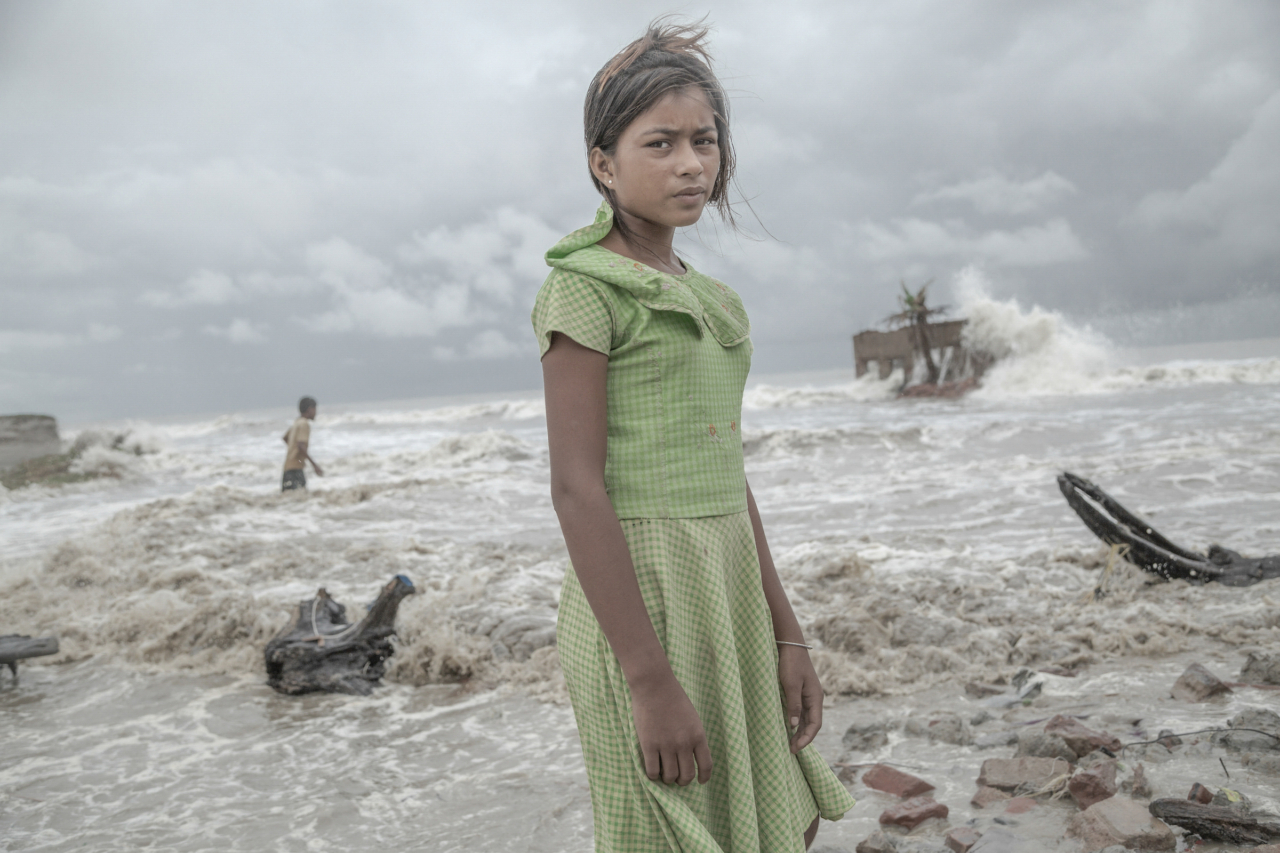 Pallavi Padua, an 11-year-old, stands for a portrait in front of her family’s tea shop in Frazerganj, Sundarbans, which has been completely destroyed by storm surges following Cyclone Amphan.