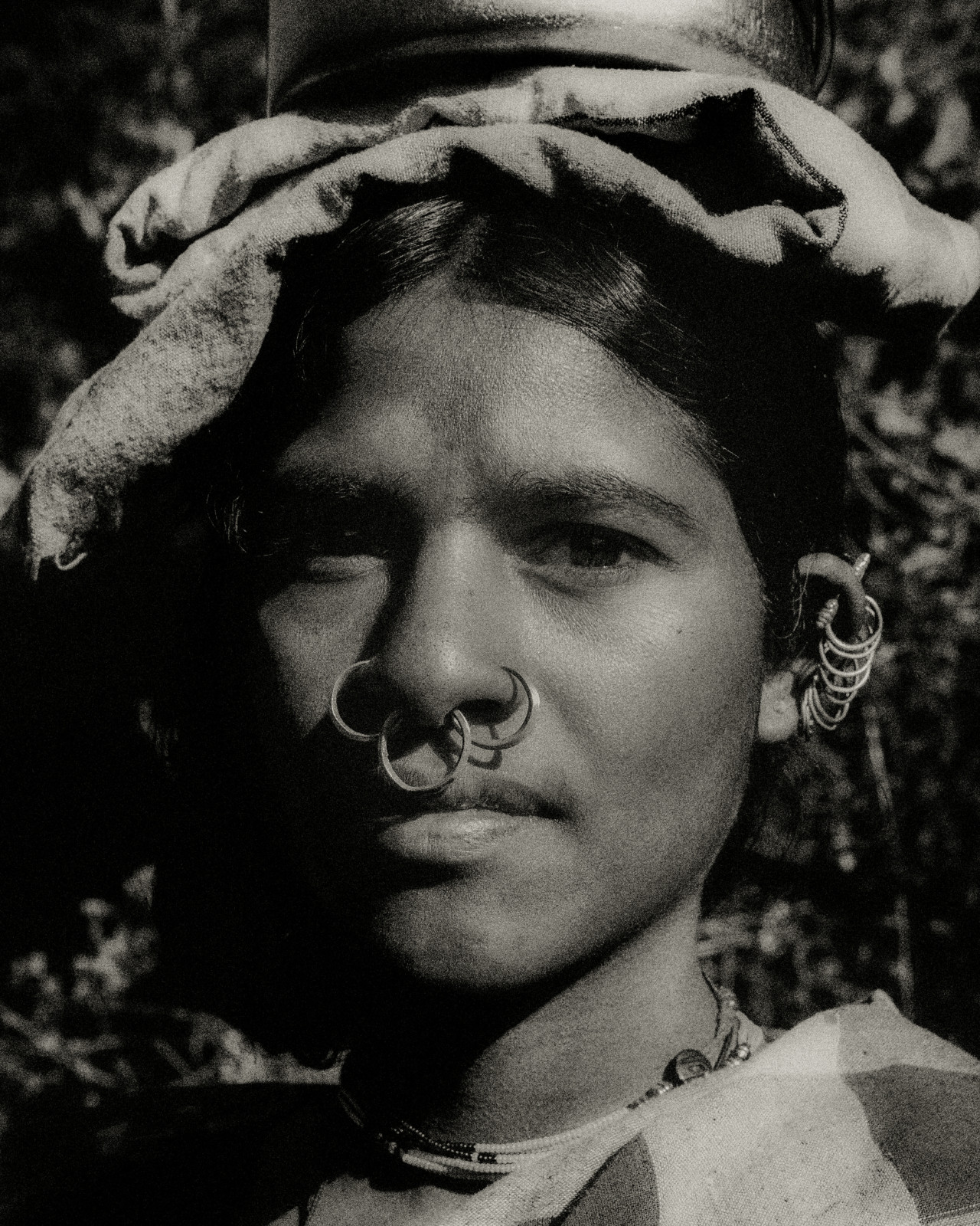 A woman from Odisha, India holds a folded cloth and bowl on top of her head.