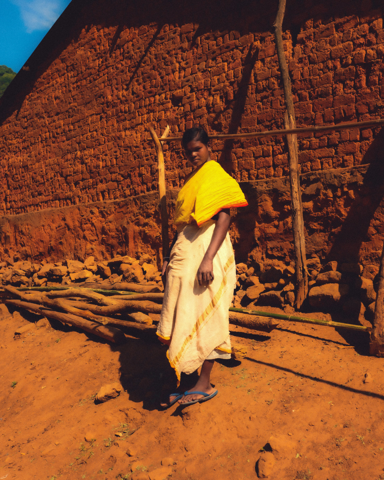 A woman form Odisha, India stands in front of a structure.