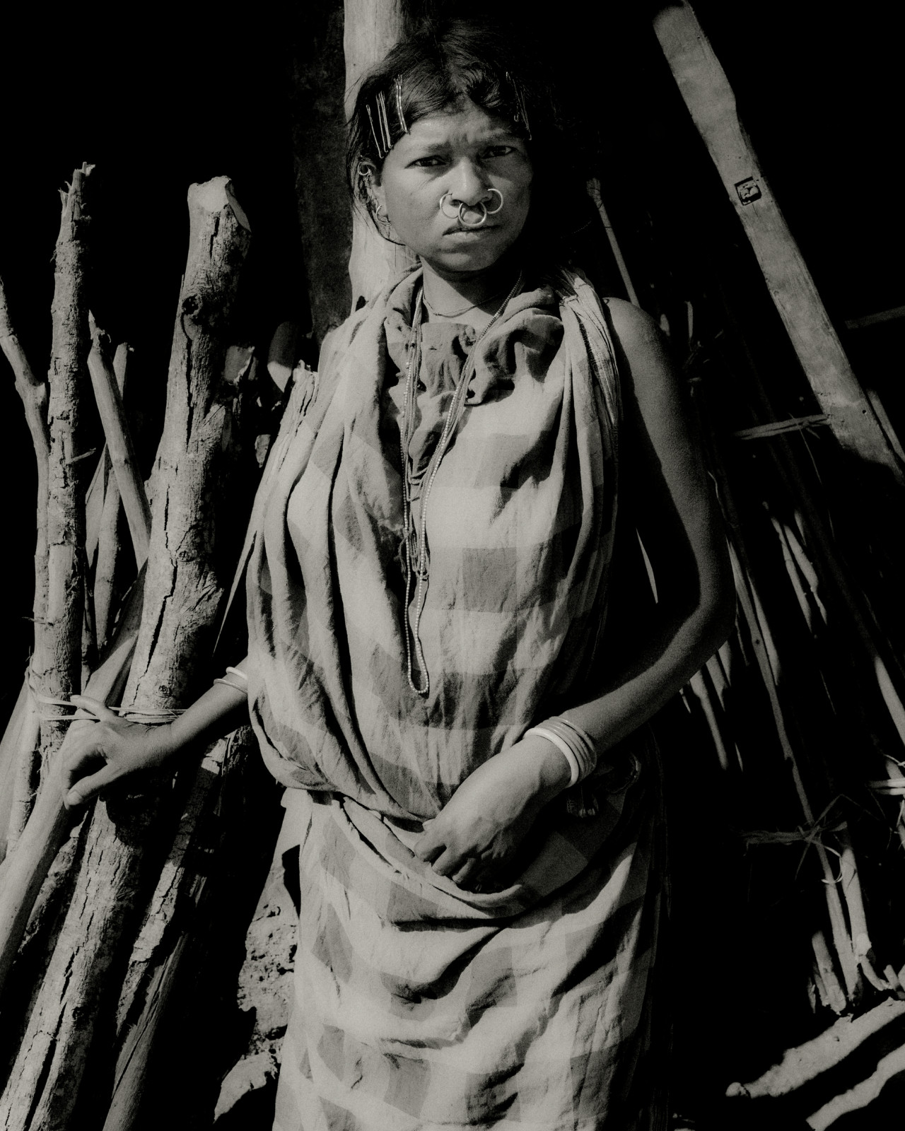 A woman from Odisha, India stands in front of a collection of tree bark.