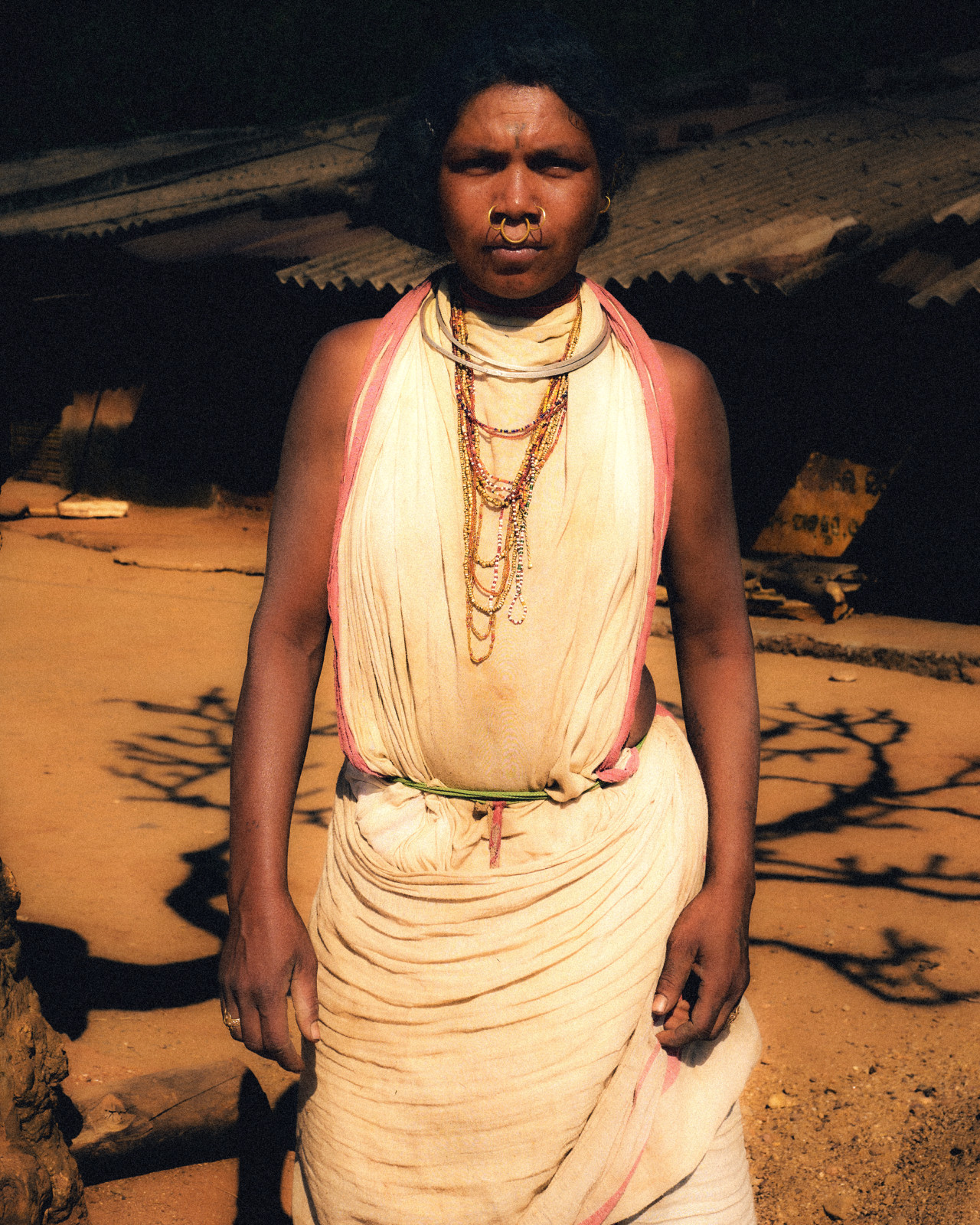 A portrait of a woman from Odisha, India standing in her community.