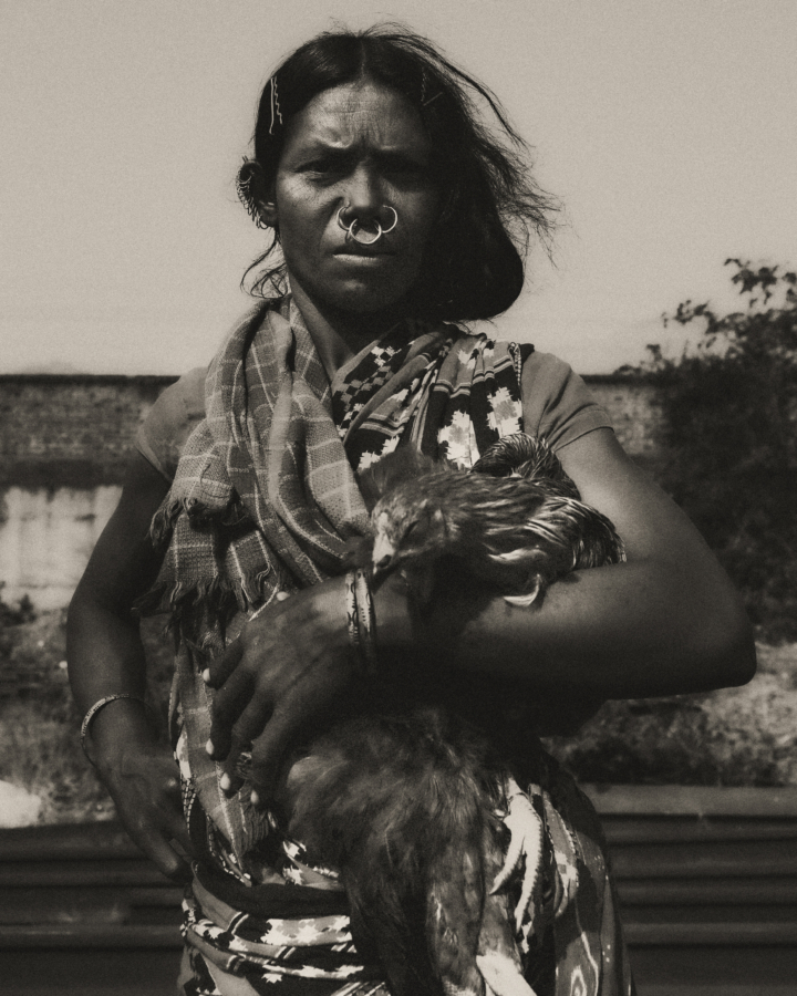 A woman from Odisha, India holds a chicken in her arms.