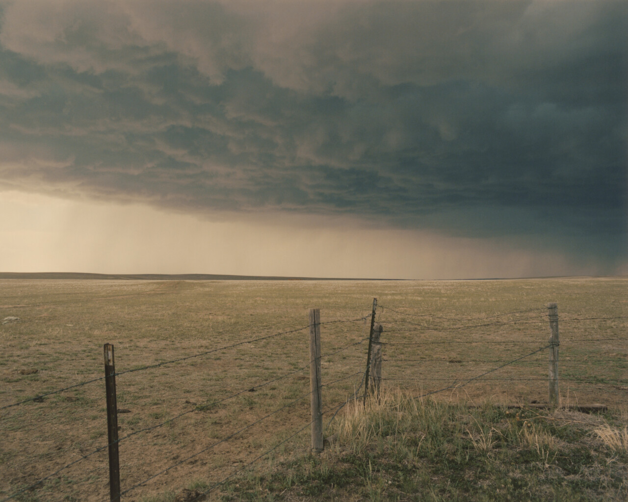 Barbed wire fence with storm clouds overhead