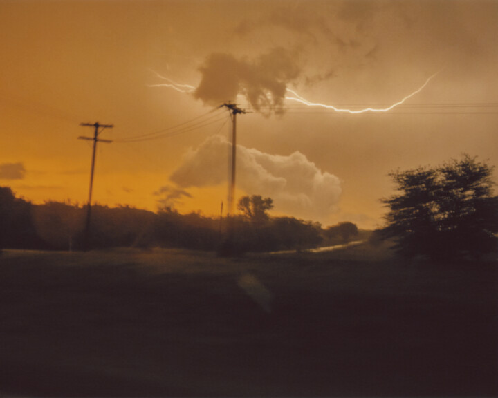 Photograph of yellowish, cloudy skies with streak of lightning.