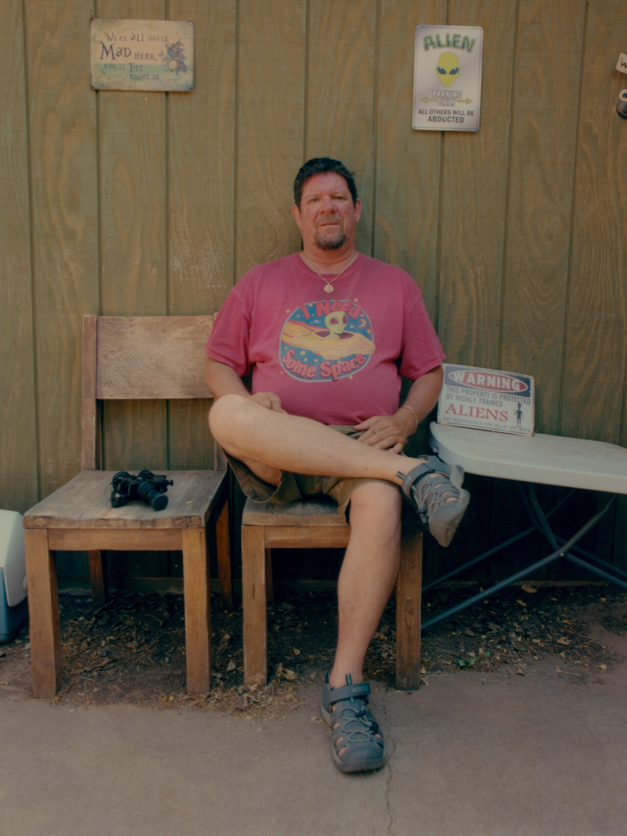 Reverend John Polk, a local UFO expert in Sedona, sits outside his home sandwiched between his night vision goggles and a sign alerting trespassers of the presence of aliens.
